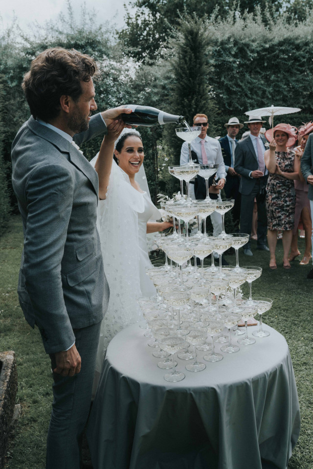 Bruidspaar schenkt champagne in champagne toren tijdens de trouwreceptie