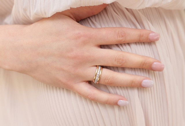 Hand met trouwringen met diamanten en een nude bruidsmanicure met glitters