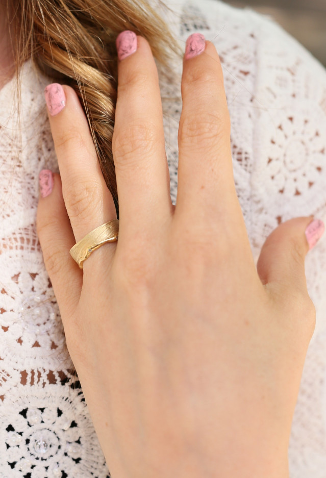 Hand met gouden trouwring en roze bruidsmanicure