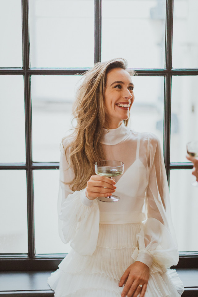 Bruid lacht met een glas drinken in haar hand