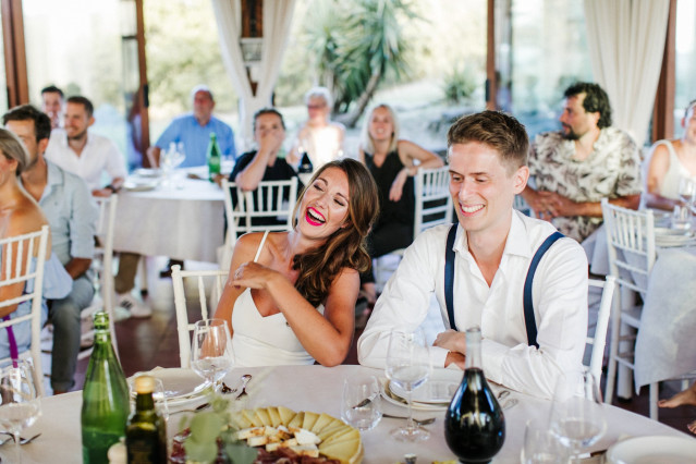Lachende bruid aan tafel bij het bruiloftsdiner